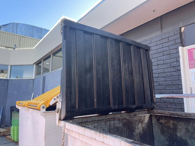 clean metal skip bin at the front of a shopping centre